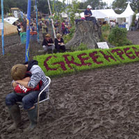 Festival Essentials List and Festival Camping Checklist - Glastonbury Festival boy with Greenpeace sign and mud