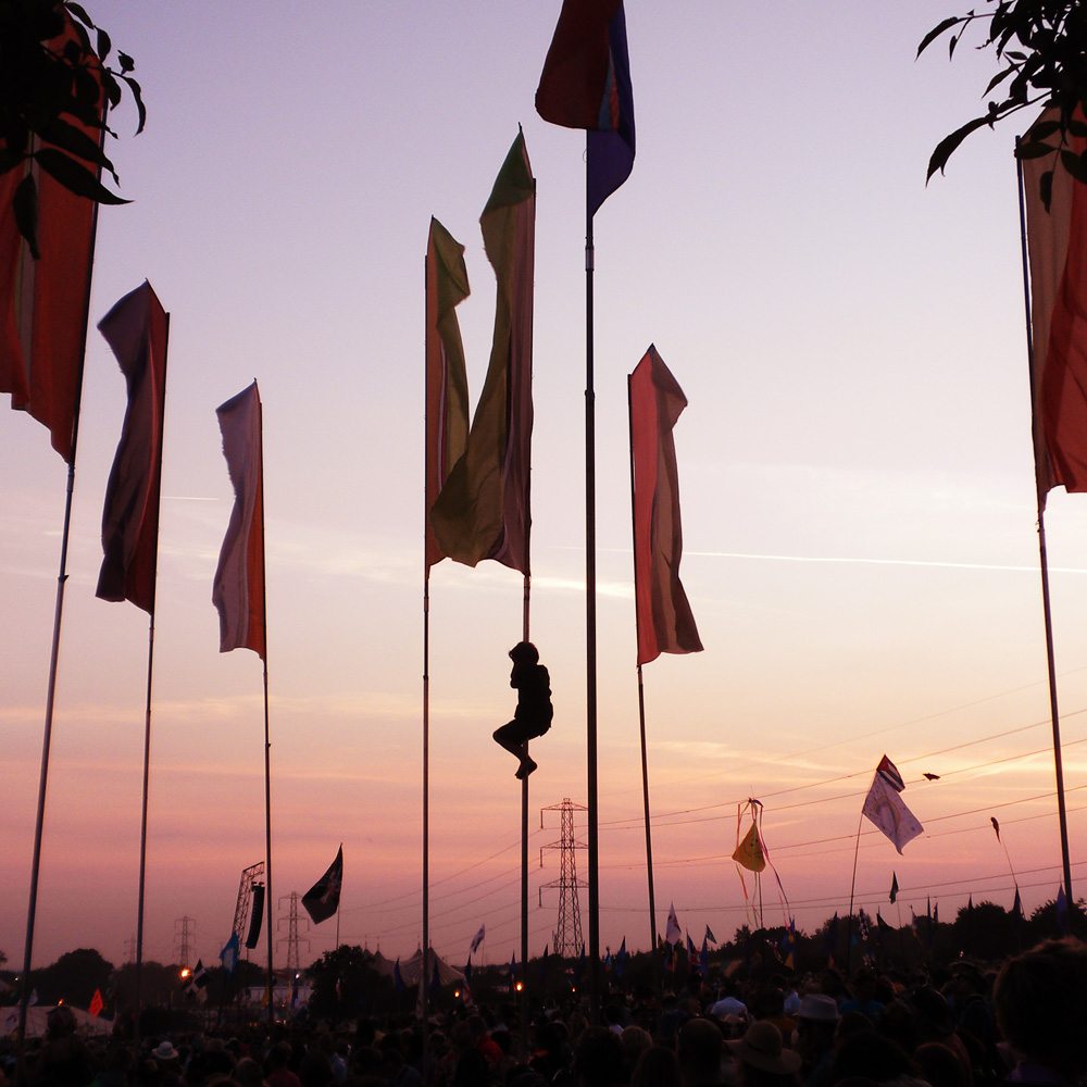 How to survive hot and wet festivals - a guide to extreme festival weather - Glastonbury Festival boy up pole in Pyramid Stage crowd