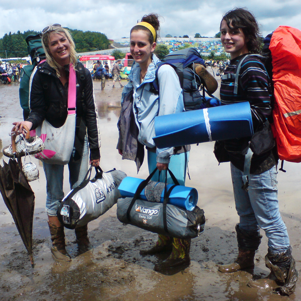 How to survive hot and wet festivals - a guide to extreme festival weather - Crystal, Bethan and sister waiting in the mud at Glastonbury Festival